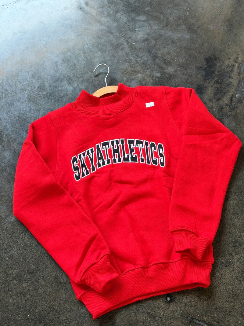 Red SKYATHLETICS crewneck sweatshirt laid flat on the gym floor