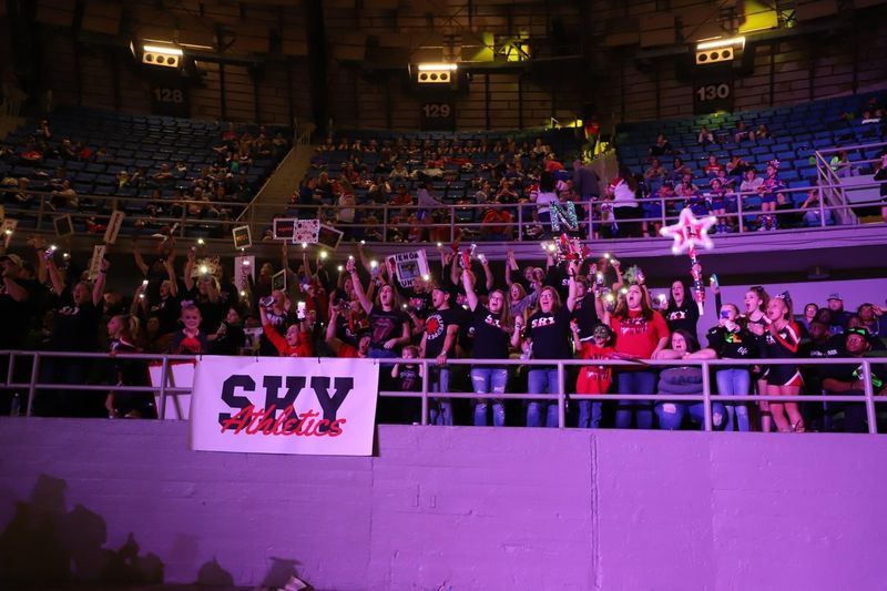 Sky families cheering in the stands with a SKY sign