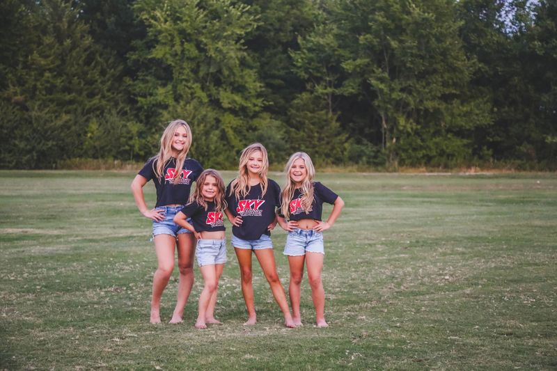 Four Sky athletes in Sky shirts posing in a field